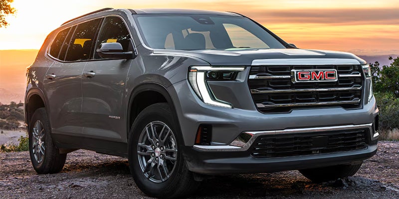 silver Acadia is parked on a large stone in the middle of a stony road