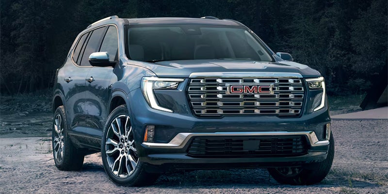 A blue Acadia parked near rocky riverbed