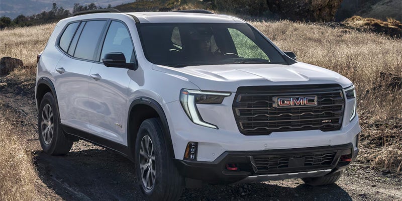 A white Acadia driving a girl on rough road