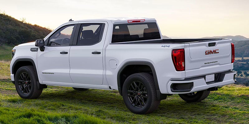 A white Sierra 1500 parked on grass rear and one side view